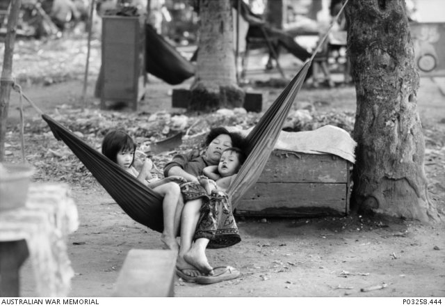 Kamodža 1993 - Na ulici v Phnom Penhu odpočívá matka v houpací síti se svým synem a dcerou, zatímco čekají na zákazníky u jejich stánku s ledem. Australian War Memorial Archive